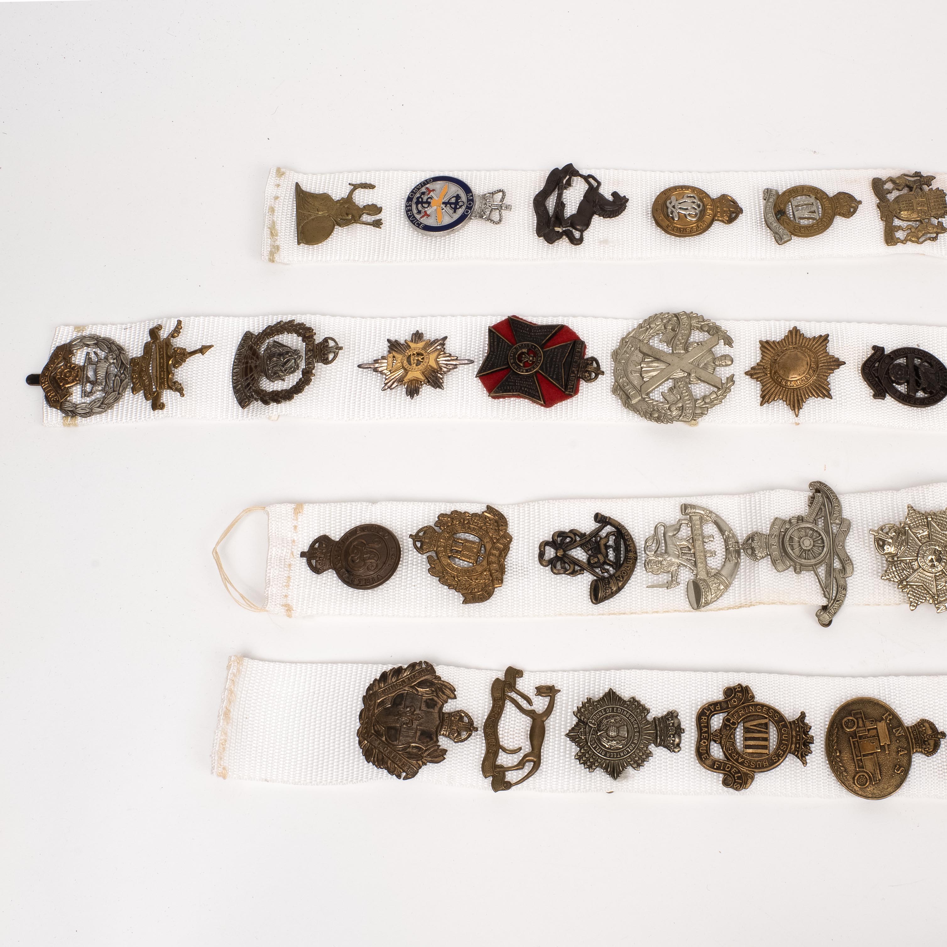 54 British Cap Badges, mounted on cloth strips 