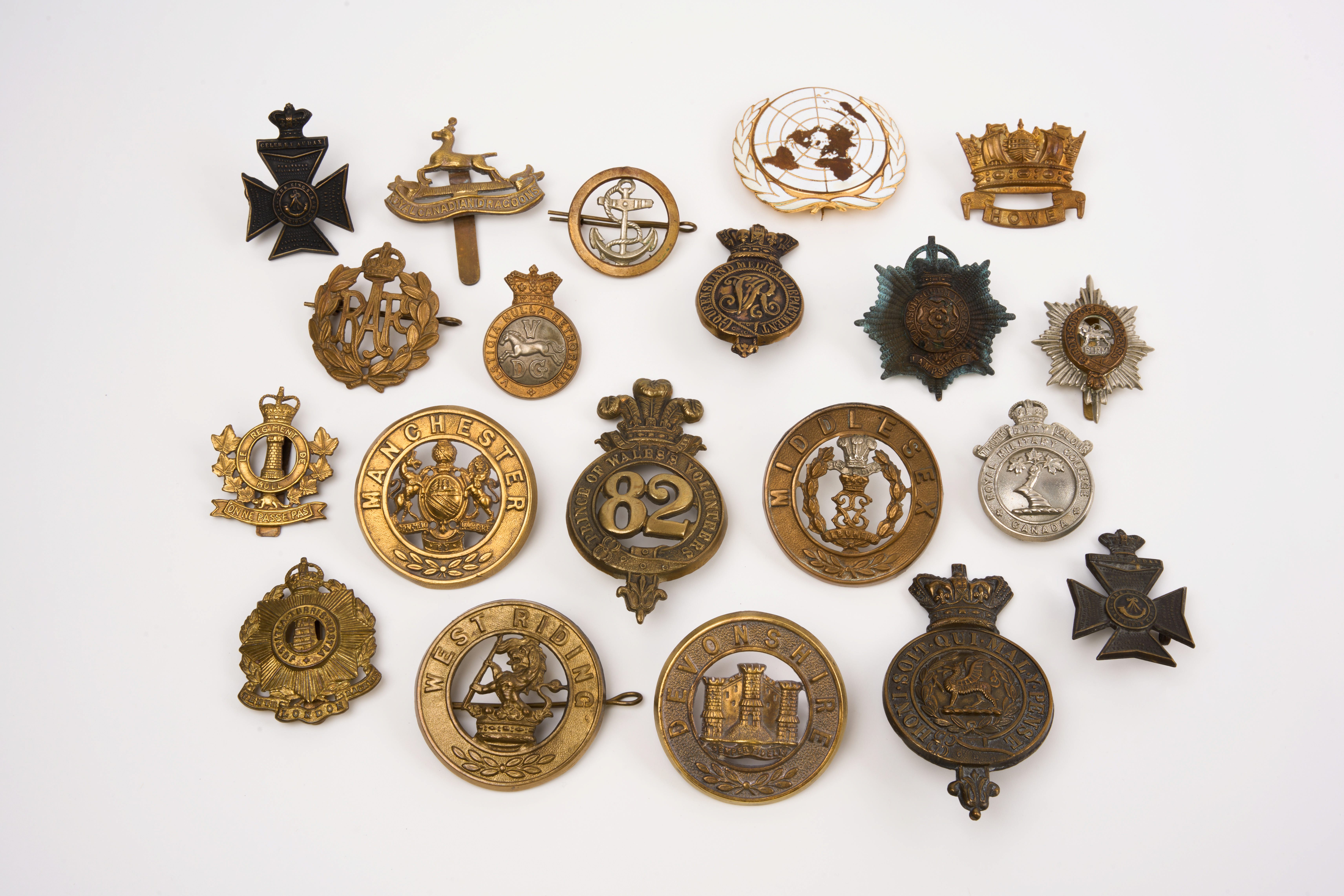 20 British and Commonwealth cap badges and helmet plates, loose in envelope