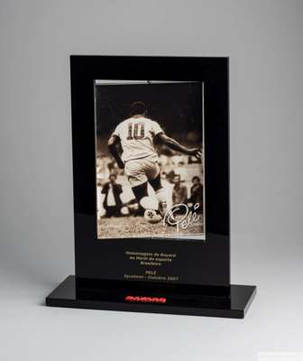 A plaque trophy presented to Pelé by Iguatemi, 
 a Brazilian firm that creates and administers shopping centers. The plaque features an image of a you