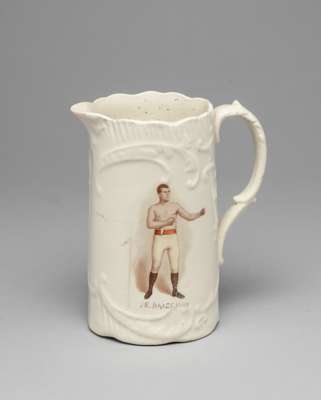 A white glazed pottery jug commemorating the Welsh heavyweight boxer Dai St. John circa 1900,
 colour printed portrait with hand painted naming, the r