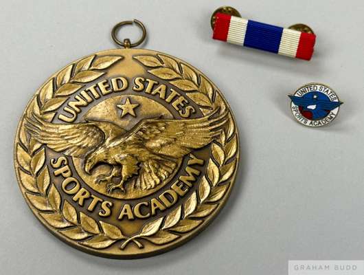 A bronze tone medallion, cloth colour bar, and enamel pin presented to Pelé by the United States Sports Academy in 1994. 
 The front of the medal feat