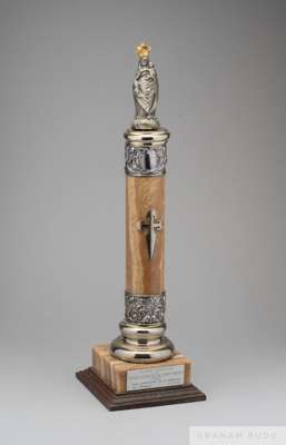 A trophy presented to Pelé composed of a silver tone figure of the crowned Mary holding the baby Jesus atop a marble column
 capped with silver repous