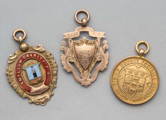 Three 9ct gold football medals, 
 comprising one enamelled and inscribed Smyllum Charity FA, the second a North Riding County FA Senior Cup runners-up