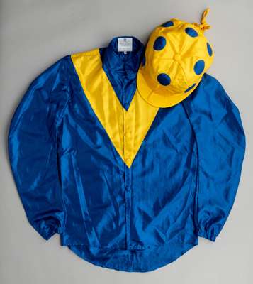 Saeed Suhail racing silks,
 bearing markers neck label for Allertons, size 36, royal blue jacket with yellow 'V', yellow cap with blue spots

 Owner o