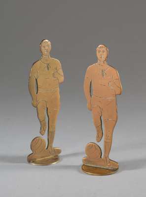Pair of brass footballer adornments early 20th century,
 each flatware footballer set on a circular base, one base drilled, (2)