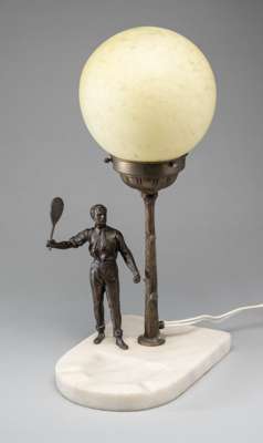 An early tennis lamp, circa 1920, 
 with spelter tennis figure, stand and marble base, 40 by 22 by 14cm., the glass sphere has a diameter of 15cm.