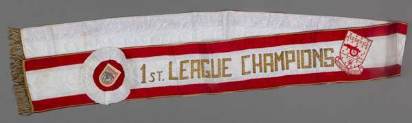 A sash worn by the Arsenal players prior to the start of the "Champions Challenge Match" at Benfica on 31st July 1971,
 red and white silk with crest'