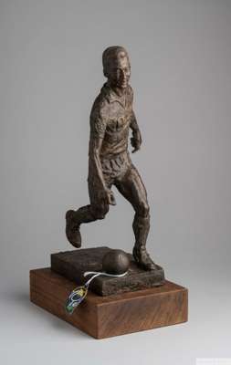 A bronze tone resin sculpture of Pelé kicking a soccer ball and wearing his No.10 shirt
 the sculpture is mounted on a wood base, 14 by 8 5/16 by 8 5/