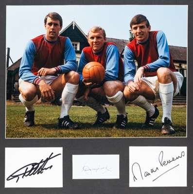 Photograph signed by West Ham United's 1966 World Cup winning trio Bobby Moore, Geoff Hurst and Martin Peters,
 featuring the three players in club ki
