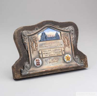 Jimmy Melia English Schools white-metal and enamel plaque
 decorated with three enamel plaques, depicting the Wembley twin towers, three lions and daf