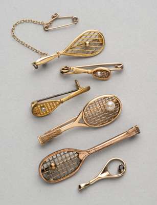 Five gilt metal tennis racquet brooches, 
 two with gilt metal tennis ball on strings, three with single pearl on strings, and another with gemset ten