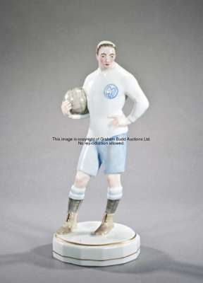A German porcelain figure of a footballer circa 1930, modelled holding a football