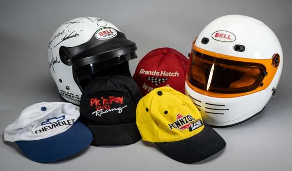 A Bell Mag 4 Kevlar Pro Series 2000 autographed helmet 
 and another Bell crash helmet, twenty-two various motor sports baseball caps including Dayton