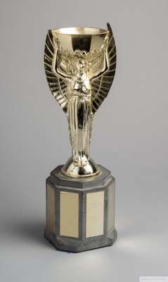 Gilt-lacquered replica of the Jules Rimet Trophy
 the octagonal stoneware base set with brass plaques listing previous winners 1930 up to 1970, 33cm h